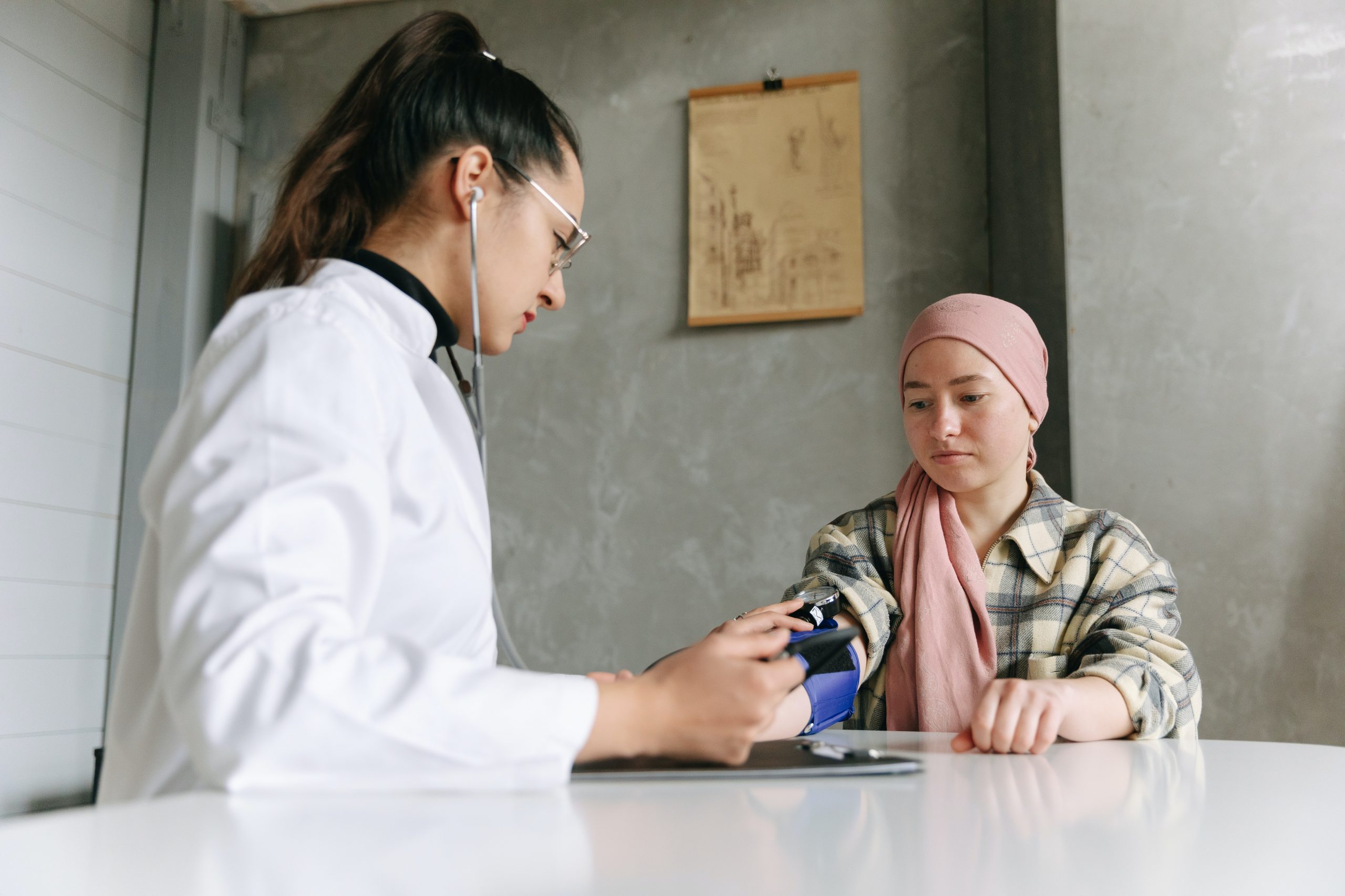 Woman wearing pink headscarf talks with her doctor