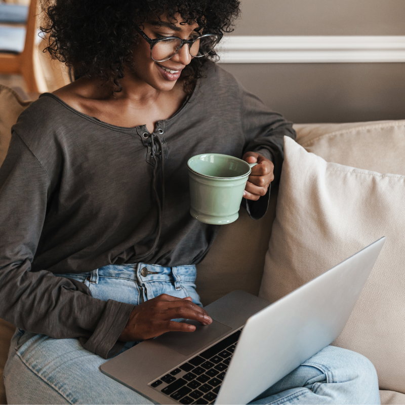 Woman looking at her laptop and drinking tea