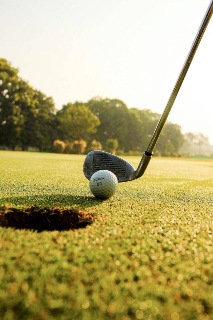Golf club lining up to hit golf ball into hole