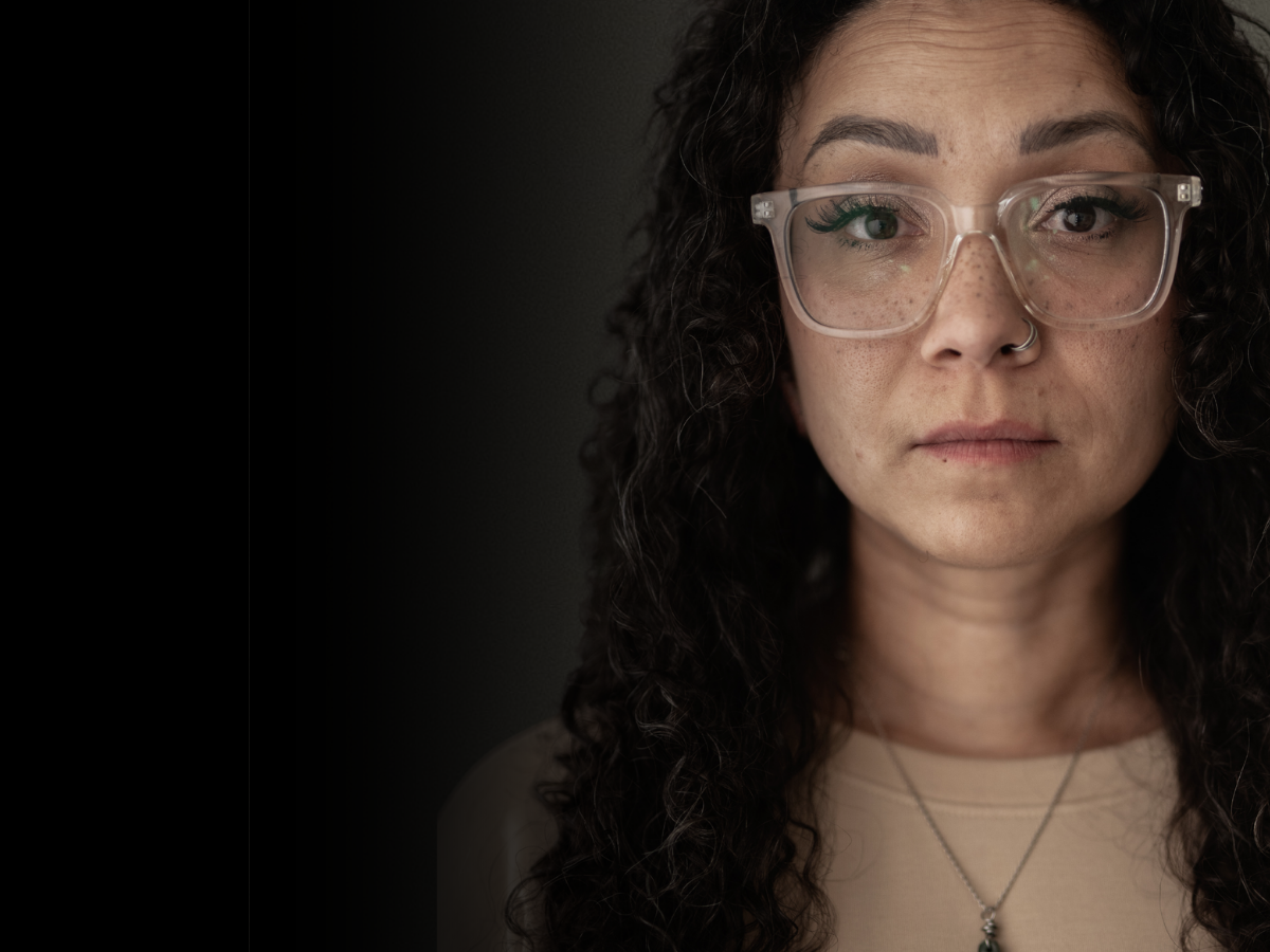 Headshot of woman wearing glasses with a dark gradient background
